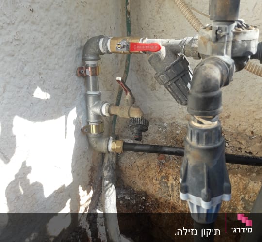 צינורות מים עם ברזים ומחברים על קיר חיצוני